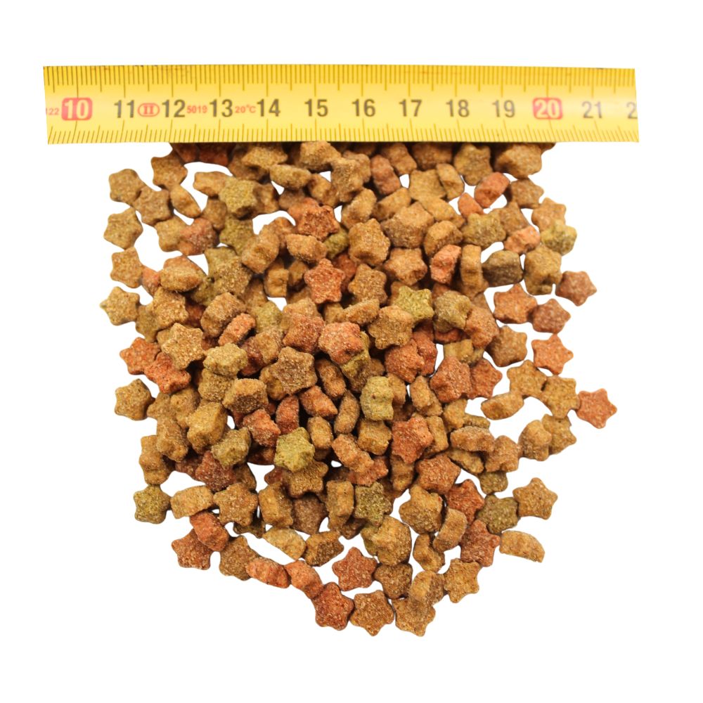 Star-shaped dry pet food kibble in brown, green, and orange colors with a yellow measuring tape showing size