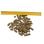 Small brown cylindrical animal feed pellets next to yellow measuring tape on white background