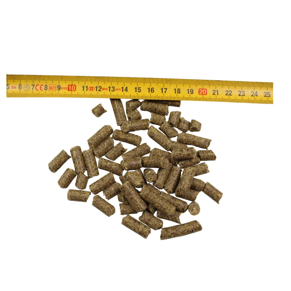 Small brown cylindrical animal feed pellets next to yellow measuring tape on white background