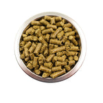 Metal bowl filled with natural brown cylindrical animal feed pellets on white background