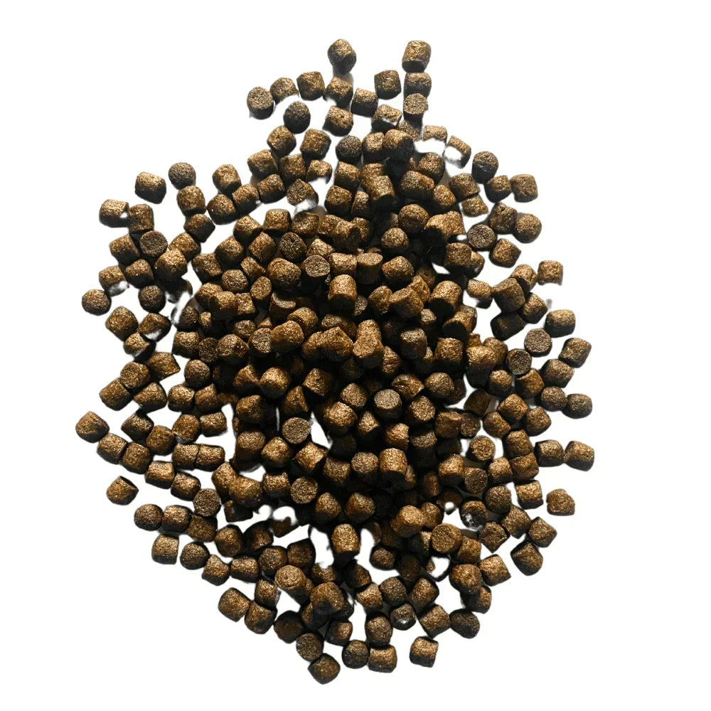 Pile of small dark brown fish food pellets on a white background