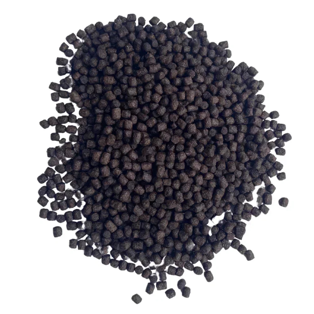 Pile of small dark brown fish food pellets on white background