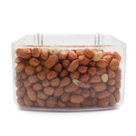 Clear plastic container filled with whole raw peanuts with skin against white background