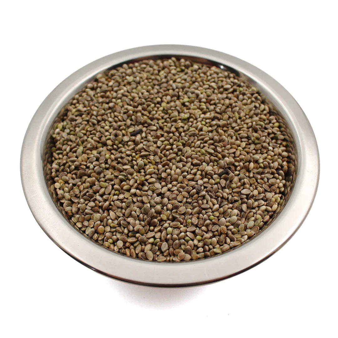 Metal bowl filled with raw hemp seeds on white background