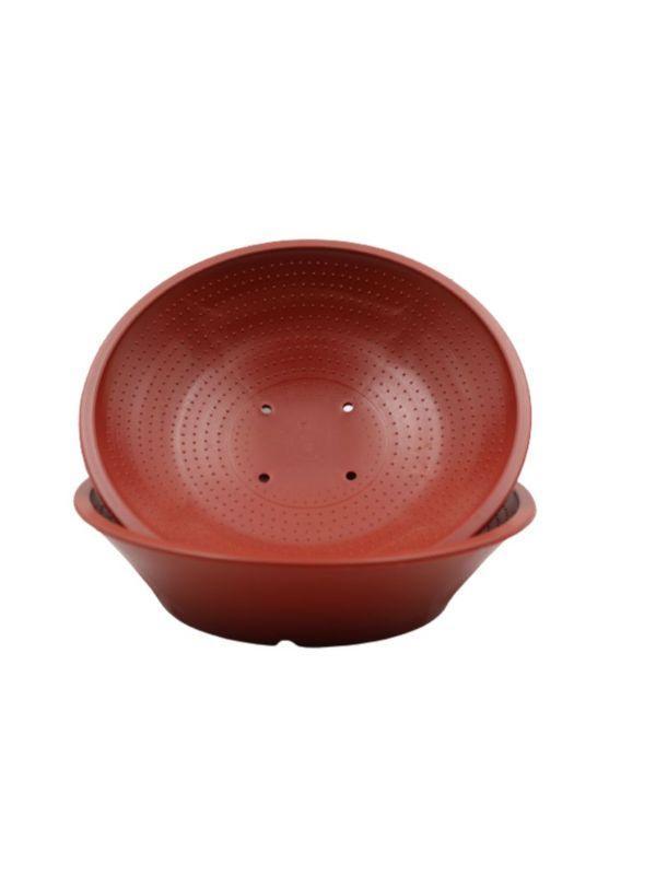 Two stacked red plastic pigeon nest bowls with drainage holes on white background