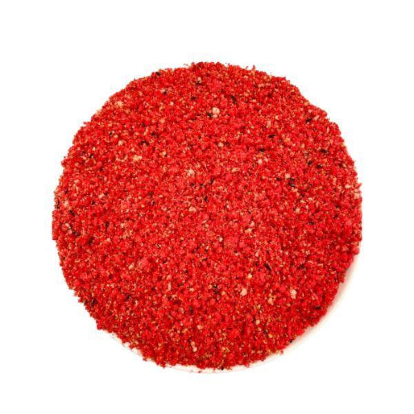Top view of coarse red spice or seasoning granules on white background