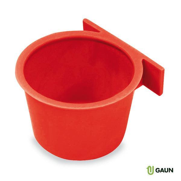 Red plastic pigeon feeder cup with mounting bracket on white background