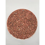bowl filled with red mineral granules and small seeds on white background