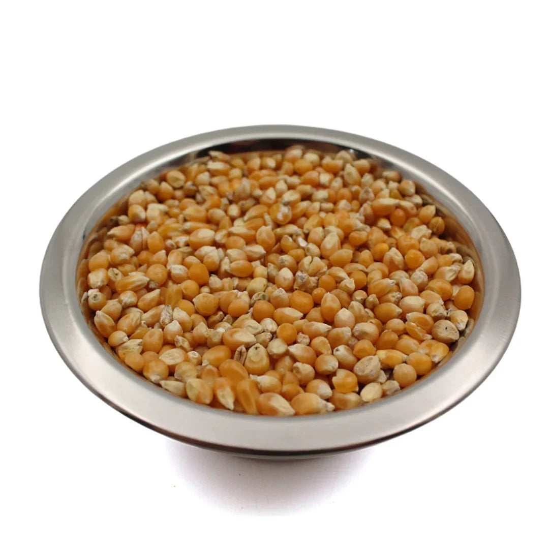 Metal bowl filled with yellow popcorn kernels on white background