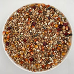 White bowl filled with a colorful mix of bird seeds and grains including corn, millet, and sunflower seeds