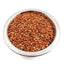 Metal bowl filled with reddish brown sorghum seeds on white background